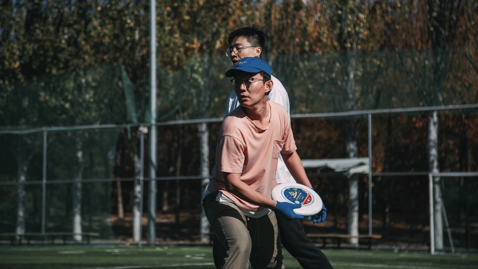 一个站在草地上覆盖着草的弗里斯比手年轻男子