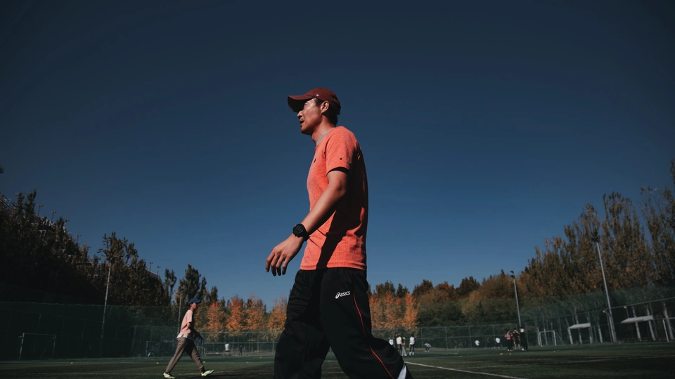 一个穿橙色衬衫的男子在草地上玩飞盘。