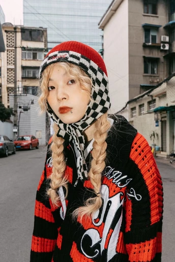 戴帽、围巾和毛衣 红唇膏的女孩在街上扎着辫子