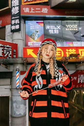 一位穿着costume的年轻女子站在街上 手里拿着剪刀。