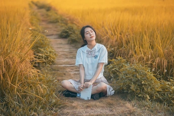 一位年轻女子坐在黄色田野中