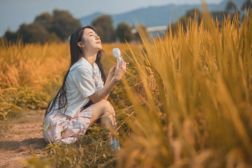 一位年轻美丽的女士穿着裙子坐在稻田里