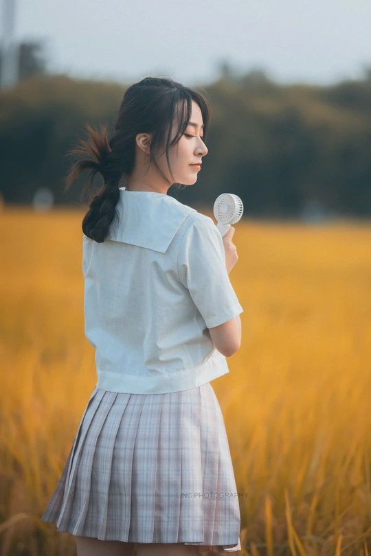 一位年轻女子手持白色花朵站在黄色田野中