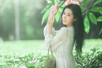 美丽的年轻女子 长发 身着传统白色长裙 手持花篮。