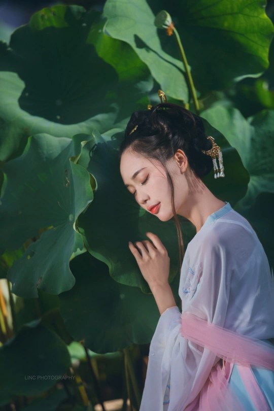 一位穿着和服的美丽女子站在莲花前面