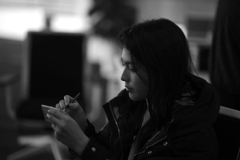 一张黑白照片 一个年轻女孩坐在房间里看着她的手机