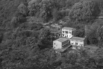 房子在山丘上 周围环绕着树木的黑白照片