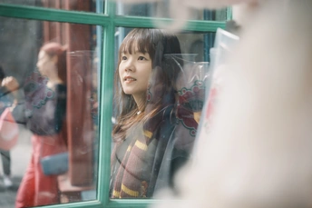 一位年轻女子在商店橱窗里看自己的倒影