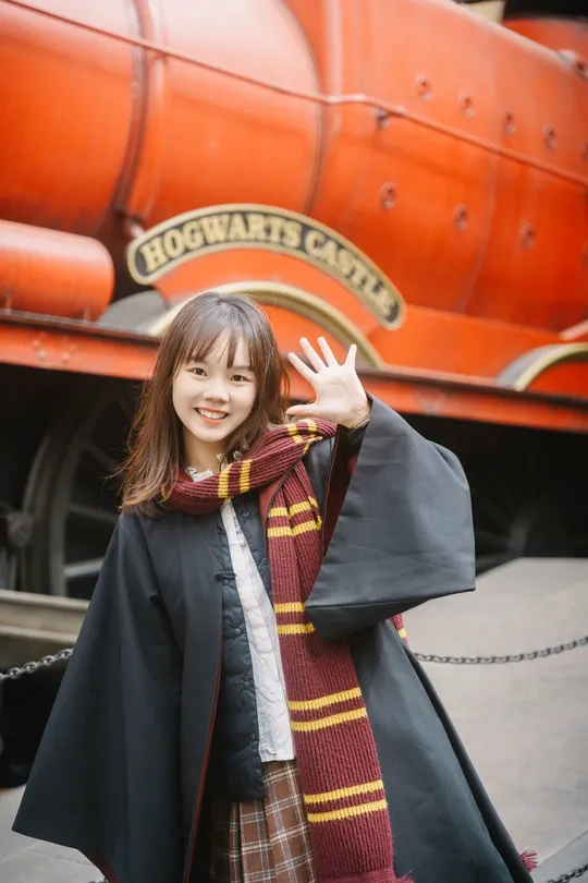 一位穿着外套和围巾的年轻女子站在一列火车前