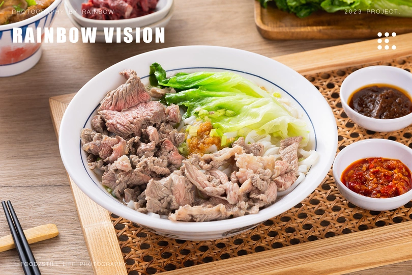 一张木桌 上面有筷子、一份肉类和蔬菜盘以及一份酱汁。