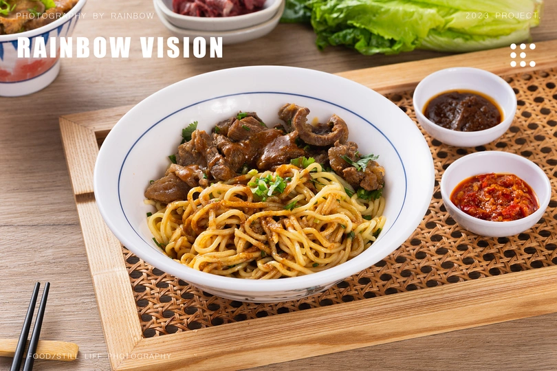 一个木制菜板 一双筷子 一个碗装酱汁 一个盘子装面条 肉类和蔬菜