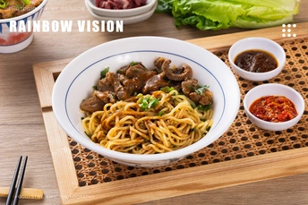 一个木制菜板 一双筷子 一个碗装酱汁 一个盘子装面条 肉类和蔬菜