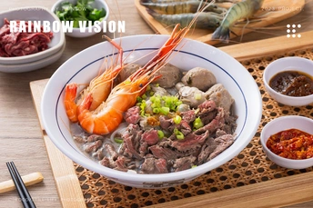 一个木制桌子上有筷子、盘子和包含肉类、虾和酱汁的食物。