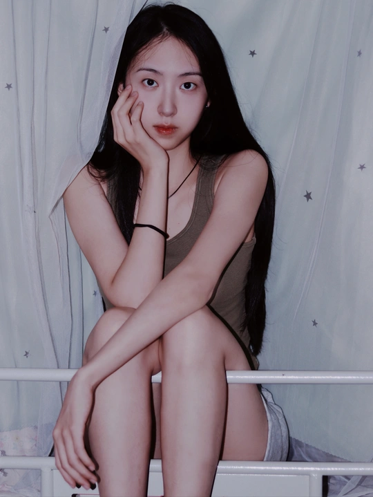 一个年轻女子坐在一张白色床上