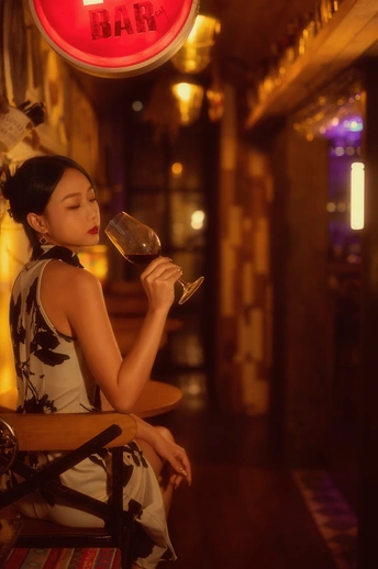 坐在酒吧或餐馆的桌子旁拿着一杯红酒的年轻女子