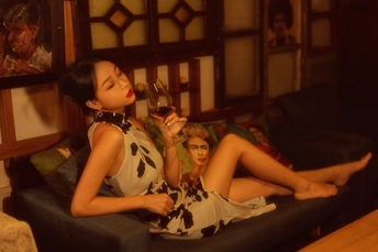 一个穿着连衣裙的年轻女子坐在沙发上喝着一杯红酒