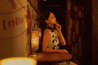 一位年轻女子坐在桌子旁的椅子上打电话