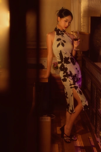 一个穿着连衣裙拿着一杯葡萄酒的年轻女子站在壁炉前