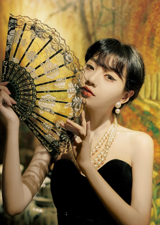 一位身穿黑色连衣裙、手持扇子和雨伞的年轻女子
