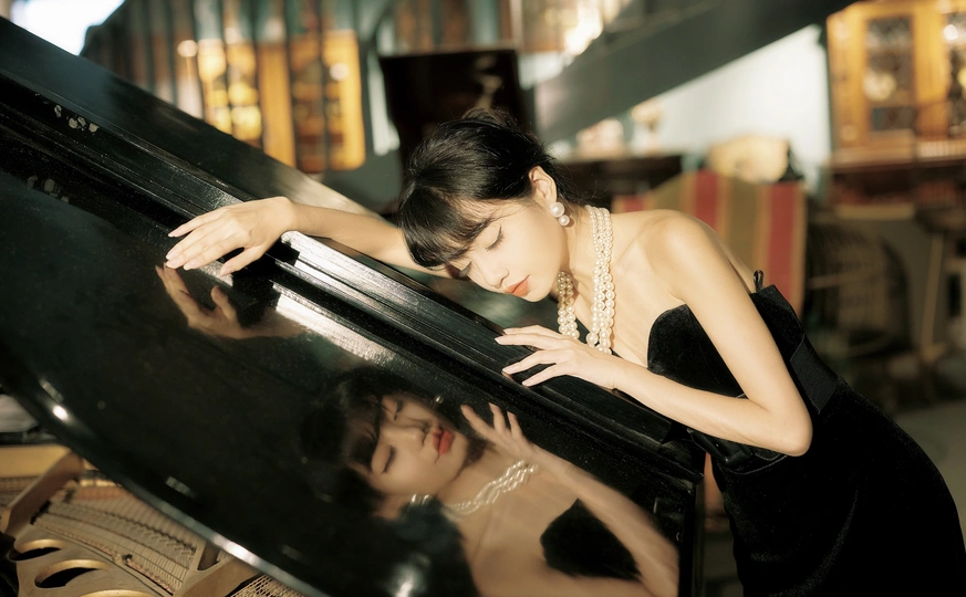 一个穿着黑色连衣裙弹钢琴的年轻女子