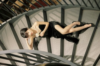 一个穿着黑色连衣裙的漂亮年轻女子躺在螺旋楼梯上