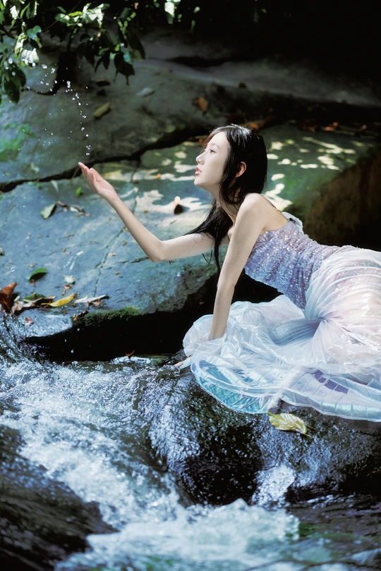 一个穿着蓝色连衣裙的美丽年轻女子漂浮在溪流中