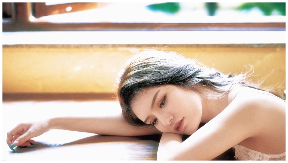 一位年轻女子躺在窗户和桌子前的地板上