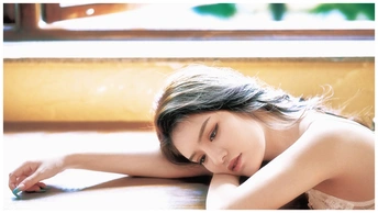 一位年轻女子躺在窗户和桌子前的地板上