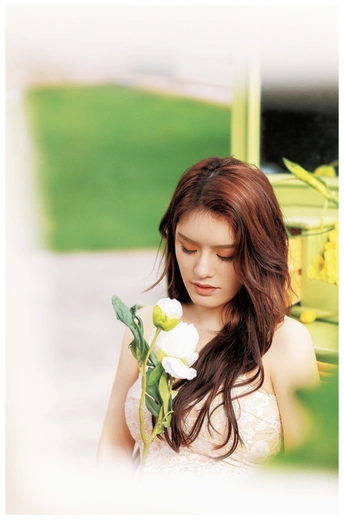 一个穿着白色连衣裙拿着花的漂亮女人