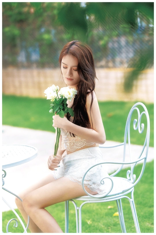 一个年轻漂亮的女人拿着一束花坐在白色的椅子上