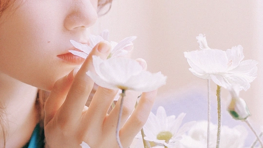 一位年轻女子将白色花朵贴在脸上