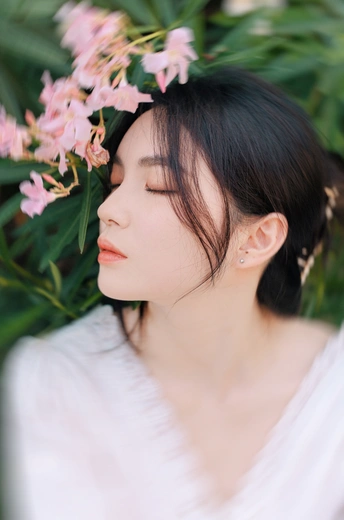 一位年轻女子穿着白色头发 闭着眼睛 头上有粉色花朵的肖像。