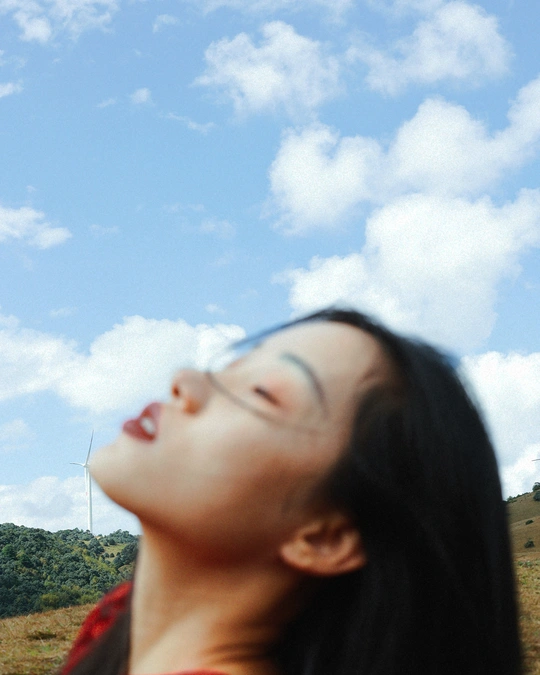 一位戴眼镜的年轻女子正在仰望她上方飞行的风筝。