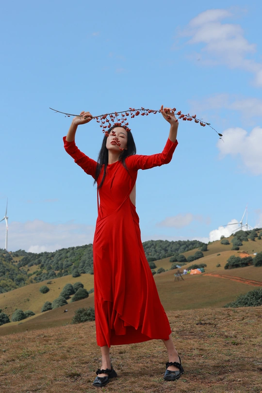 一位穿着红裙子的女人 头上戴着一只插着花的风筝。