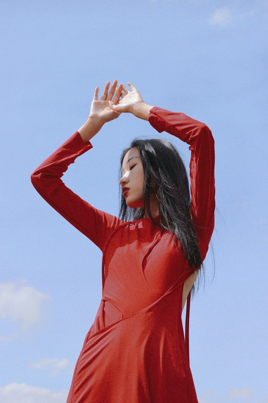 一位穿着红色连衣裙站在蓝色天空前的女人
