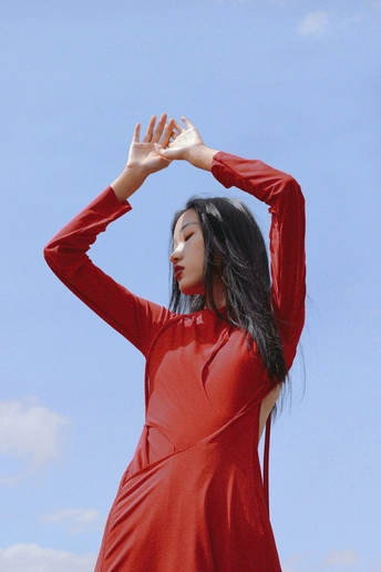 一位穿着红色连衣裙站在蓝色天空前的女人