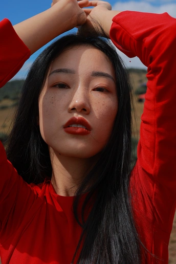 一位年轻女子穿着红衬衫 将头发扎在后面 摆出姿势。