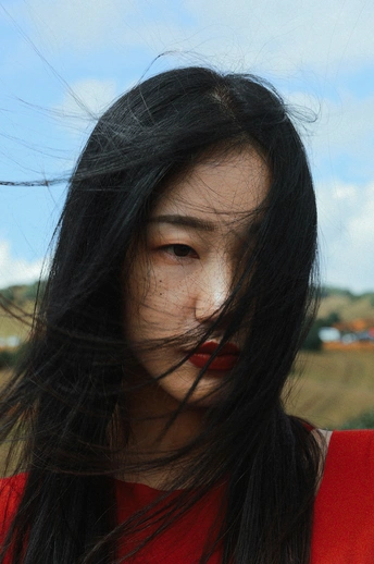 一位长发飘飘的年轻女子 涂着红唇 对着镜头微笑。