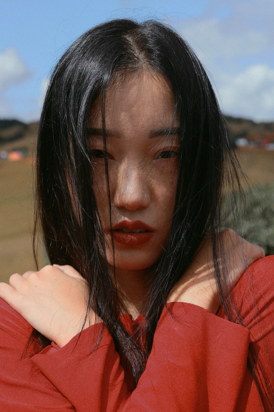 一位穿着红衬衫的年轻女子将她的脸颊靠近她的肩膀。