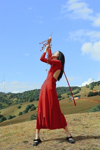 一位穿着红裙子的女人手里拿着一个风筝在天空中。