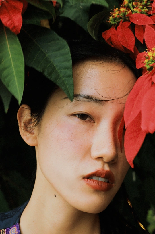 一位头戴红花的年轻女子正在为肖像摆姿势。