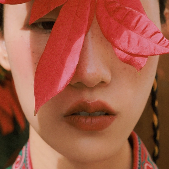 一位戴红帽子的年轻女子 脸上覆盖着粉色花朵。