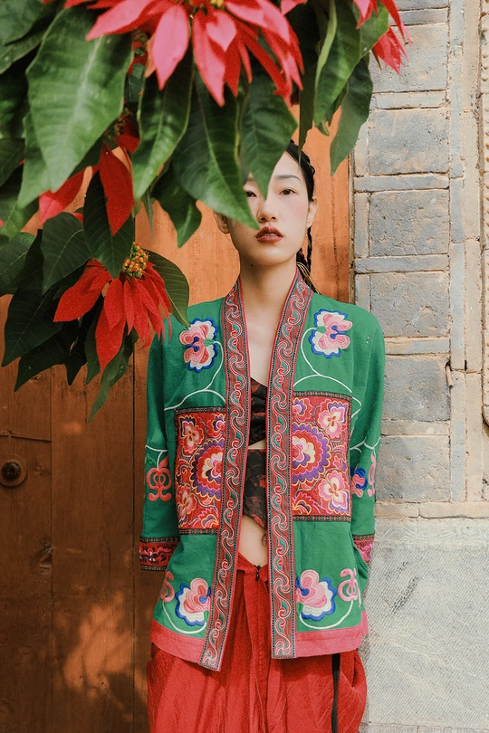 一位穿着传统服装的年轻女子站在一栋建筑物的门前