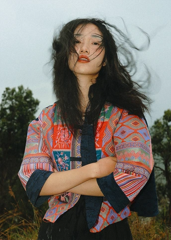 一位穿着彩色衬衫 长发飘飘 站在田野中的年轻女子