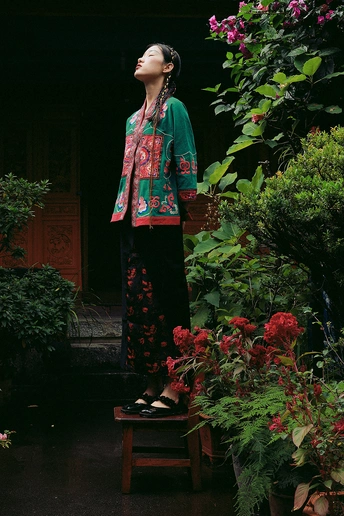 站在一所房子前面有植物和一把伞的一个年轻女子