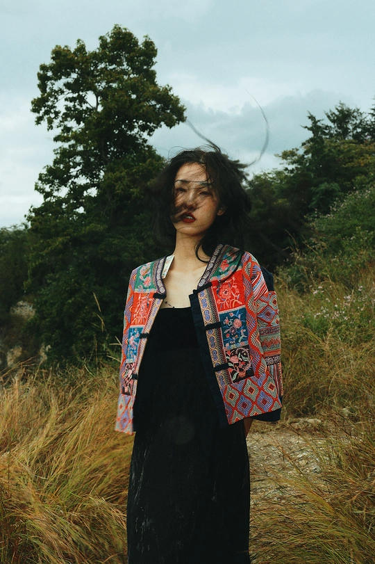 一位穿着长裙的女士站在一片高草丛中