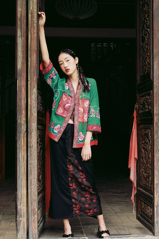 一位身着中国传统服装的年轻女子在寺庙的木门前摆姿势