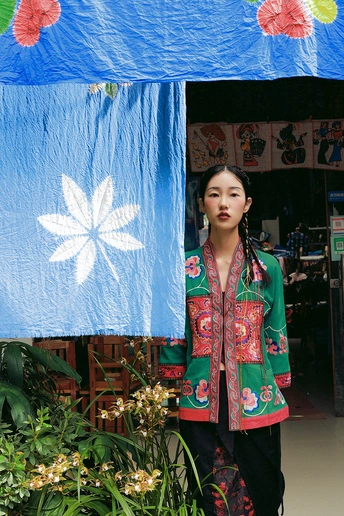 一位年轻女子站在一把蓝色雨伞下