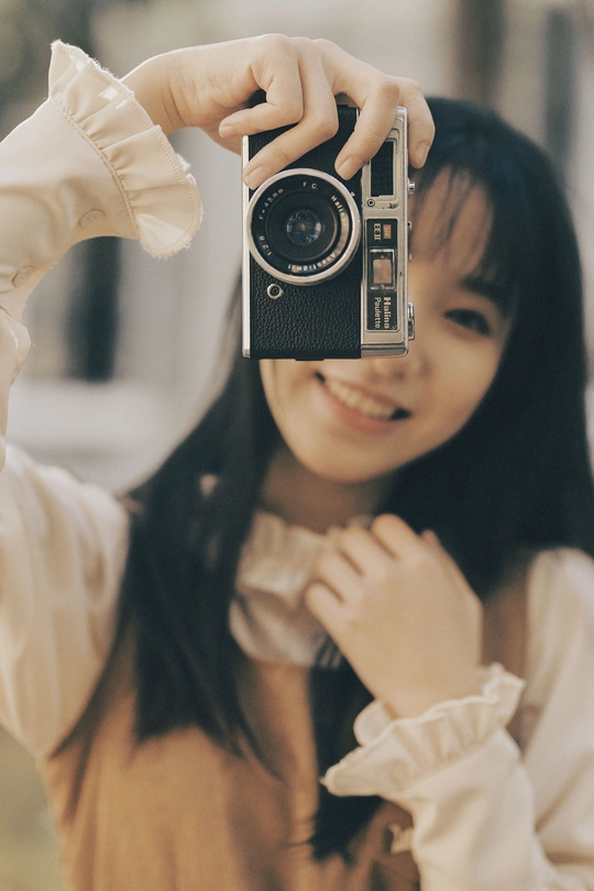 一个年轻女子拿着一部老相机拍照
