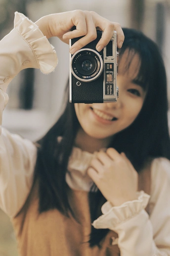 一个年轻女子拿着一部老相机拍照